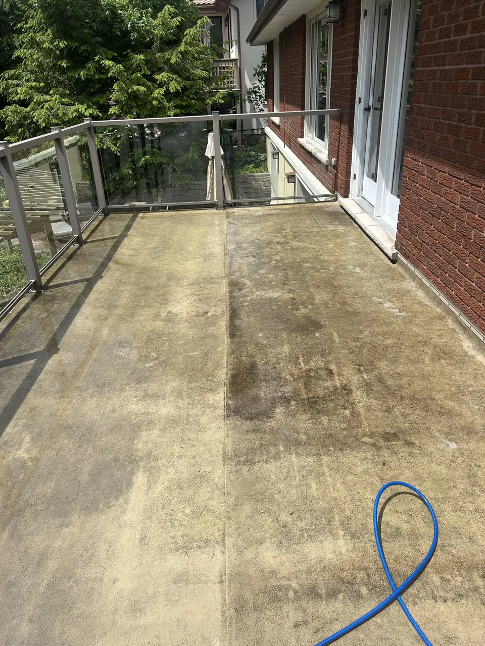 Concrete balcony half-way through pressure washing in Kingston